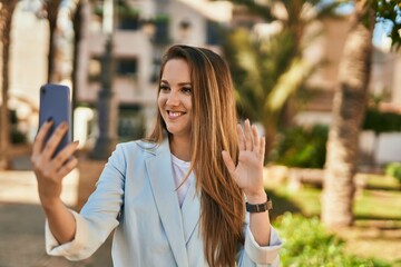 Young blonde businesswoman making video call using smartphone at the city.