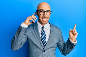 Bald man with beard having conversation talking on the smartphone smiling happy pointing with hand and finger to the side