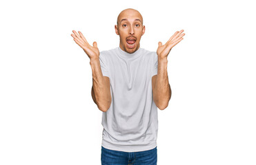 Fototapeta premium Bald man with beard wearing casual white t shirt celebrating crazy and amazed for success with arms raised and open eyes screaming excited. winner concept