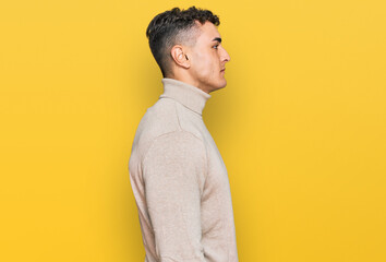 Hispanic young man wearing casual turtleneck sweater looking to side, relax profile pose with natural face with confident smile.