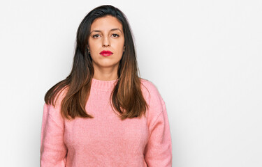 Beautiful hispanic woman wearing casual winter sweater with serious expression on face. simple and natural looking at the camera.