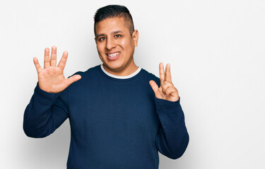 Fototapeta premium Young latin man wearing casual clothes showing and pointing up with fingers number eight while smiling confident and happy.