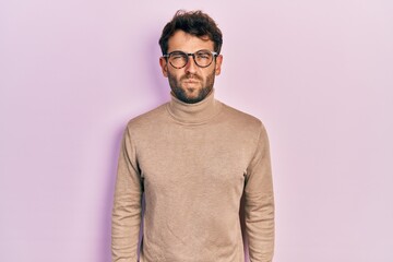 Obraz premium Handsome man with beard wearing turtleneck sweater and glasses skeptic and nervous, frowning upset because of problem. negative person.