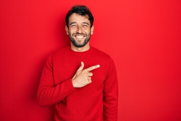Handsome man with beard wearing casual red sweater cheerful with a smile on face pointing with hand...