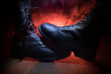War concept. Old military shoe in a dark toned foggy background. Creative concept of conflict...
