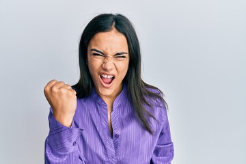 Fototapeta premium Young brunette woman wearing casual clothes angry and mad raising fist frustrated and furious while shouting with anger. rage and aggressive concept.