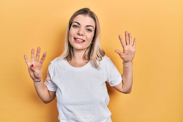 Beautiful caucasian woman wearing casual white t shirt showing and pointing up with fingers number nine while smiling confident and happy.