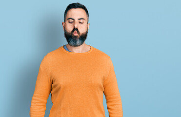 Hispanic man with beard wearing casual winter sweater making fish face with lips, crazy and comical gesture. funny expression.