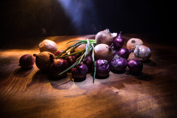 Vegetable concept. Onions in dark on wooden table. Selective focus