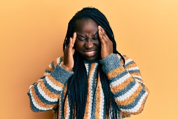 Young black woman with braids wearing casual winter sweater with hand on head, headache because stress. suffering migraine.