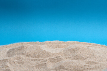 Fototapeta na wymiar Beach sand pile isolated on blue background.