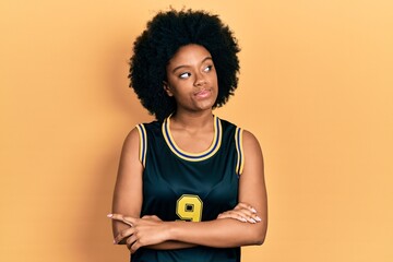 Young african american woman wearing basketball uniform smiling looking to the side and staring away thinking.