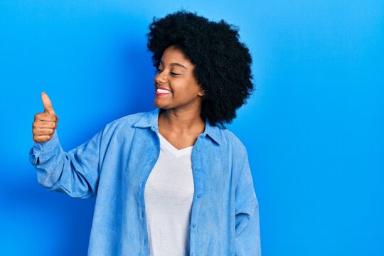 Young african american woman wearing casual clothes looking proud, smiling doing thumbs up gesture to the side