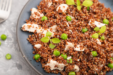 Quinoa porridge with green pea and chicken on ceramic plate on a gray concrete background. Top view, selective focus.