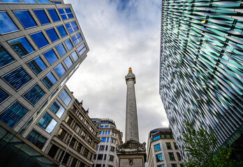 Fototapeta na wymiar The Monument to the Great Fire of London, usually called simply The Monument, is a Doric column located in the City of London, UK. The Monument is now surrounded by the modern architecture of London.