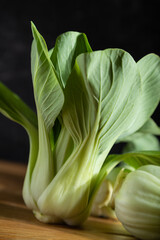 Fresh green bok choy or pac choi chinese cabbage on a gray wooden background. Dark, moody. Side view, close up, selective focus.