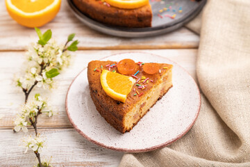 Orange cake and a cup of coffee on a white wooden background. Side view, selective focus.