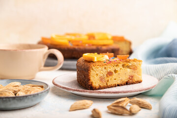 Orange cake with almonds and a cup of coffee on a white concrete background. Top view, selective focus.