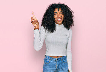 Young african american girl wearing casual clothes pointing finger up with successful idea. exited and happy. number one.