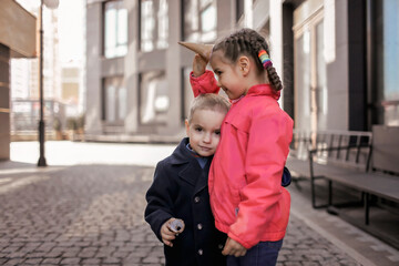 Naklejka premium Pretty girl eating ice cream at street over urban background, funny candy girl have fun and hold waffle cone like a horn of unicorn, sweet dessert, street food, outside lifestyle