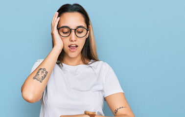 Young hispanic woman wearing casual white t shirt looking at the watch time worried, afraid of...