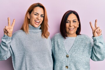 Latin mother and daughter wearing casual clothes smiling with happy face winking at the camera...