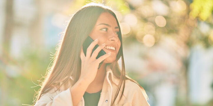 Young hispanic girl smiling happy talking on the smartphone at the park.