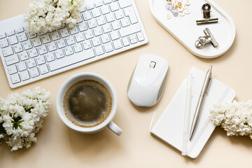 Neutral color tabletop with pc keyboard, notepad and white flowers, home office objects