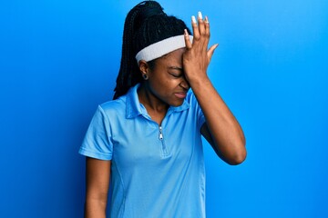 African american woman with braided hair wearing tennis player uniform surprised with hand on head...