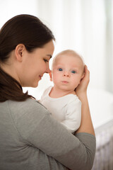 Portrait of happy mother and baby, parent and little kid relaxing at home. Family having fun together.
