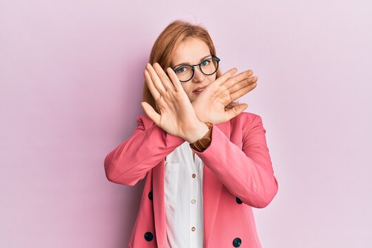 Young caucasian woman wearing business style and glasses rejection expression crossing arms and palms doing negative sign, angry face