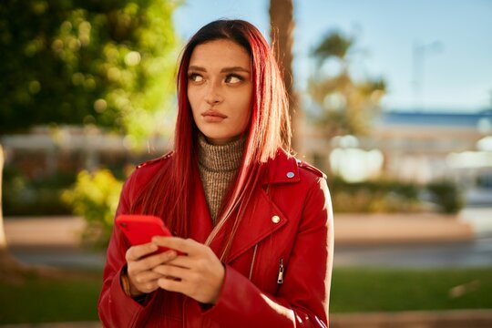 Young caucasian girl with serious expression using smartphone at the city.