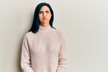 Fototapeta premium Young caucasian woman wearing casual winter sweater puffing cheeks with funny face. mouth inflated with air, crazy expression.