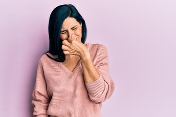 Young caucasian woman wearing casual clothes smelling something stinky and disgusting, intolerable...