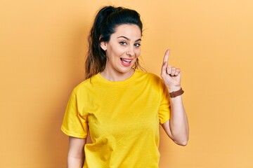 Young hispanic woman wearing casual clothes smiling with an idea or question pointing finger up with happy face, number one