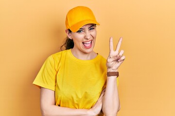 Young hispanic woman wearing delivery uniform and cap smiling with happy face winking at the camera...