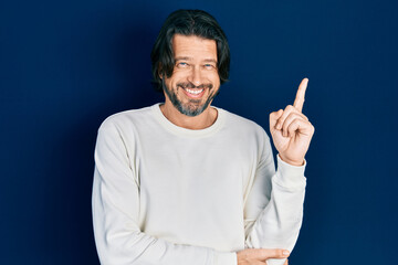 Naklejka premium Middle age caucasian man wearing casual clothes with a big smile on face, pointing with hand and finger to the side looking at the camera.