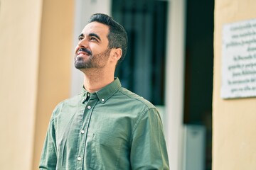 Young hispanic man smiling happy standing at the city.