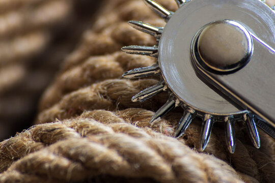Wartenberg wheel on the background of ropes for shibari, kimbaku. Bdsm backgrounds