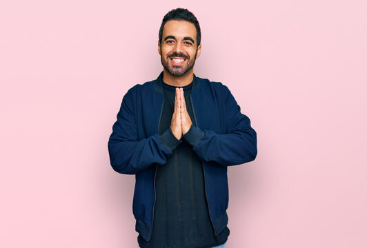 Young hispanic man wearing casual clothes praying with hands together asking for forgiveness smiling confident.