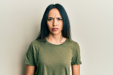 Young hispanic girl wearing casual t shirt skeptic and nervous, frowning upset because of problem....