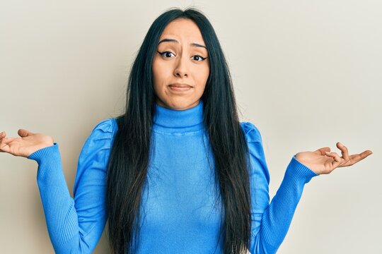 Young hispanic girl wearing casual clothes clueless and confused with open arms, no idea and doubtful face.