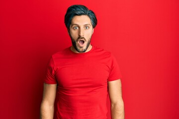 Young hispanic man wearing casual red t shirt afraid and shocked with surprise and amazed expression, fear and excited face.