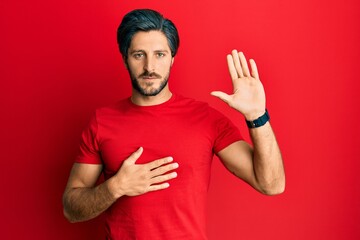 Young hispanic man wearing casual red t shirt swearing with hand on chest and open palm, making a loyalty promise oath