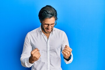 Young hispanic man wearing casual clothes and glasses celebrating surprised and amazed for success with arms raised and eyes closed