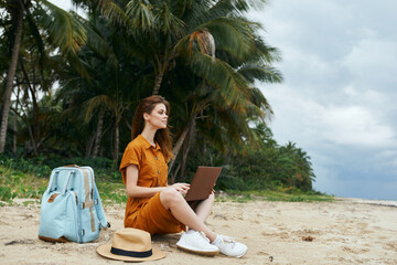 woman on the island sitting on the sand travel laptop work freelance