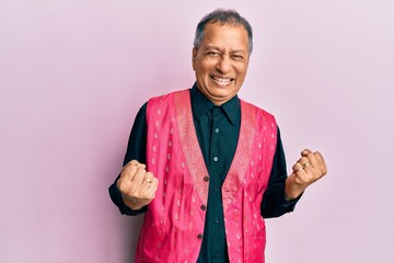 Middle age indian man wearing traditional indian clothes excited for success with arms raised and eyes closed celebrating victory smiling. winner concept.