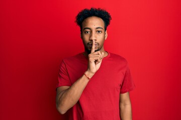 Young african american man with beard wearing casual red t shirt asking to be quiet with finger on lips. silence and secret concept.