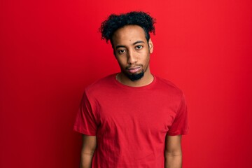 Young african american man with beard wearing casual red t shirt depressed and worry for distress, crying angry and afraid. sad expression.