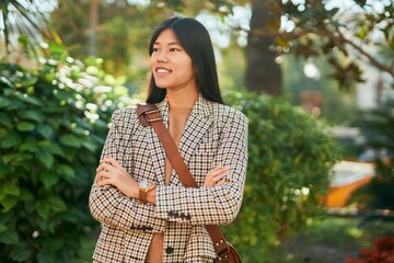 Young asian businesswoman with arms crossed smiling happy at the park,